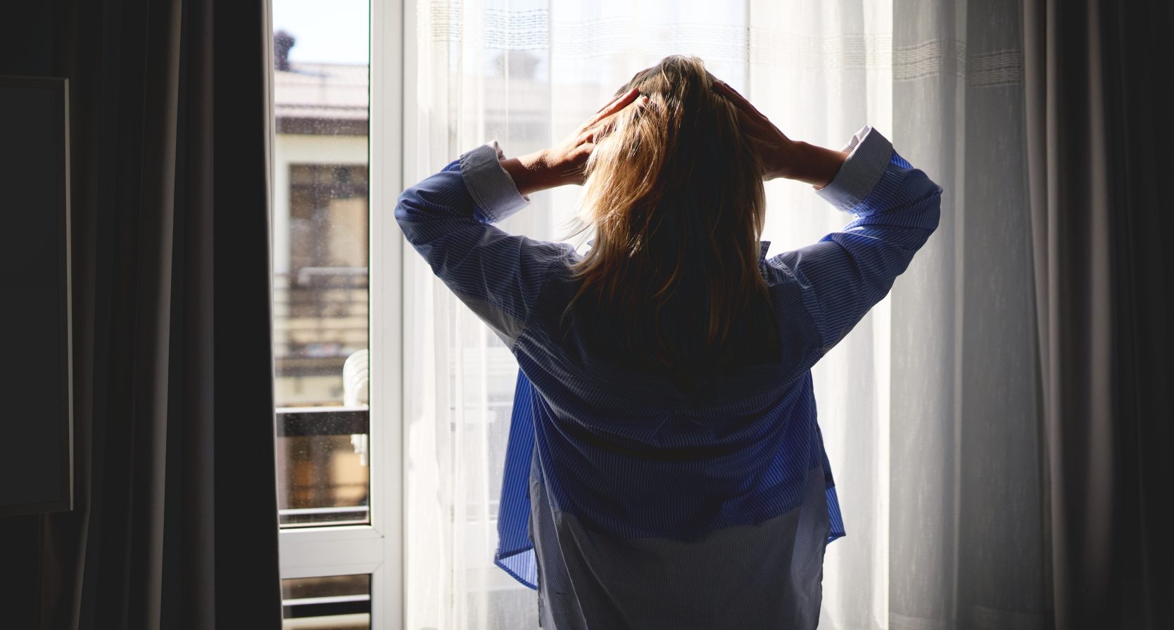 Vrouw staat voor het raam en is in shock want ze heeft meer broers en zussen