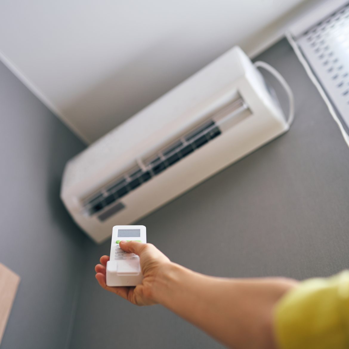 Arm met afstandsbediening doet de airco van de buurman aan
