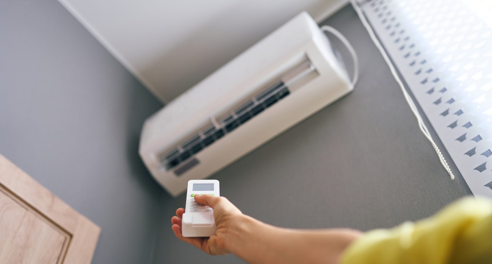 Arm met afstandsbediening doet de airco van de buurman aan